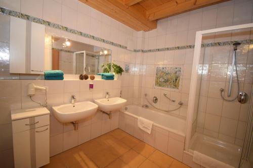 布格哈斯拉赫斯特格沃德豪斯兰德酒店的浴室配有2个盥洗盆、淋浴和浴缸。