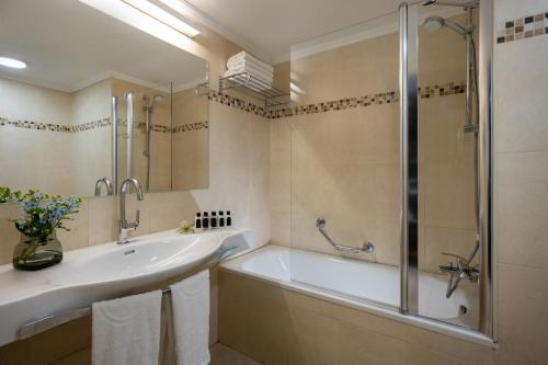 拉马特甘Kfar Maccabiah Business & Sport Hotel的带浴缸、水槽和淋浴的浴室