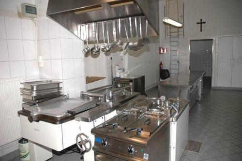 Jüchen尼克劳斯克勒斯特酒店的一间大厨房,配有不锈钢用具和十字架