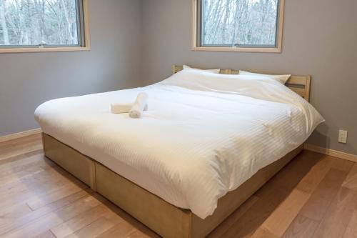 白马村Bluebird Chalets by The Hakuba Collection的卧室内的一张床铺,配有白色棉被