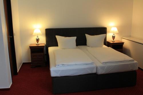 埃森埃森城市酒店的一间卧室配有一张床,两台桌子上放着两盏灯