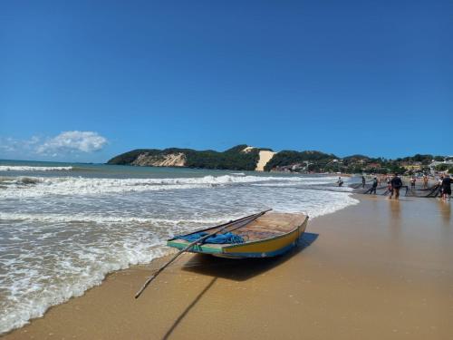 纳塔尔Ilusion Flats Aconchego de Ponta Negra的和水里的人一起在海滩上乘船