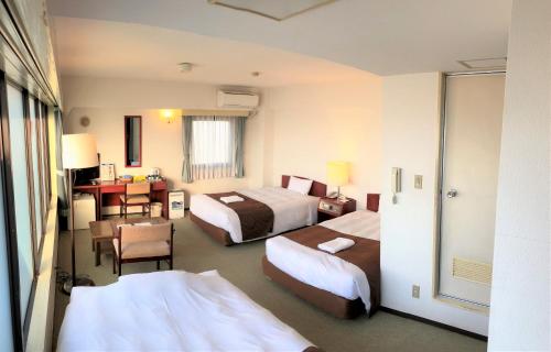 东京Sky Heart Hotel Koiwa的酒店客房配有两张床和一张书桌