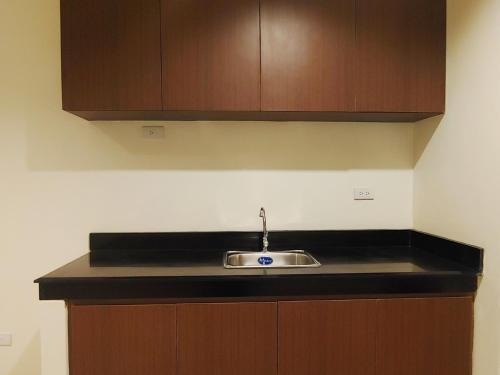 马尼拉Kaizen Suites的一个带水槽和木柜的厨房台面
