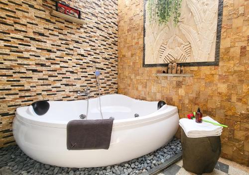 雅加达Verse Lite Hotel Gajah Mada的带浴缸的浴室和砖墙