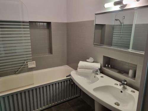 Feurs康迪酒店的一间带水槽、浴缸和镜子的浴室