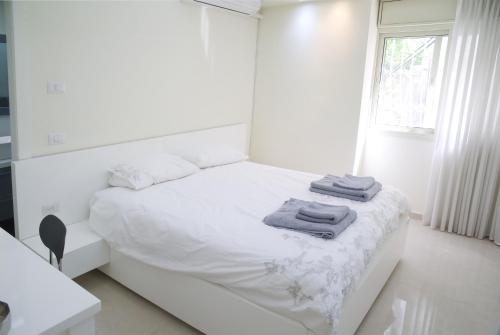 特拉维夫Dizengoff - Lovely family apartment 3 rooms.的白色卧室,配有带毛巾的床