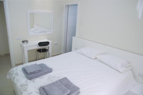 特拉维夫Dizengoff - Lovely family apartment 3 rooms.的卧室配有白色的床和2条毛巾