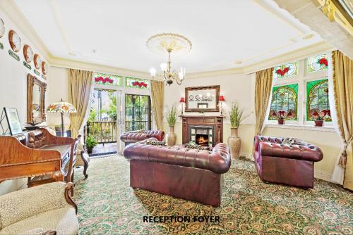悉尼查林顿酒店的客厅配有皮革家具和钢琴