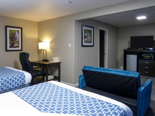 安大略Rodeway Inn & Suites的酒店客房设有两张床、一张桌子和一台电视。
