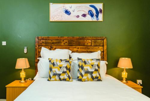 哈博罗内Birdville BNB Guest House的一间卧室配有一张带绿色墙壁的床和两盏灯。