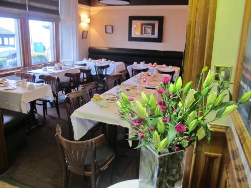 古罗克大三角帆酒店的花瓶里带白色桌子和鲜花的用餐室