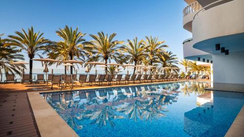 马贝拉Hapimag Resort Marbella的一个带椅子的游泳池,棕榈树