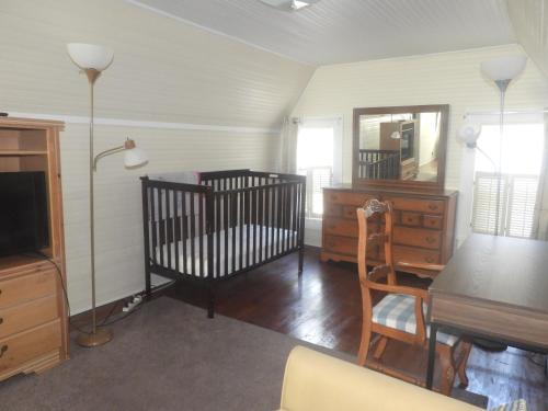 Brick House Retreat的一间设有两张婴儿床、一张桌子和镜子的房间