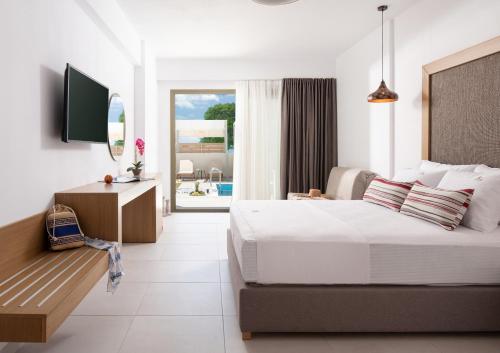 尼基季Imagine Luxury Suites的一间卧室配有一张床、一张书桌和一台电视