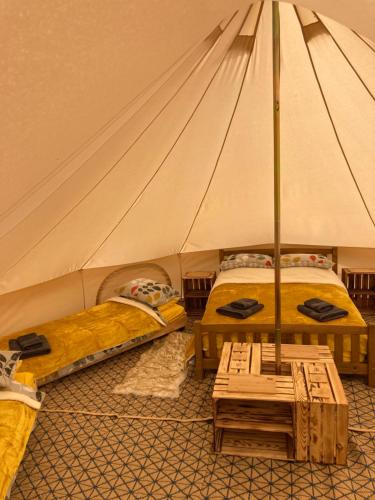 利克Roaches Retreat Eco Glampsite - Wallaby Way Bell Tent的帐篷配有两张床和一张桌子
