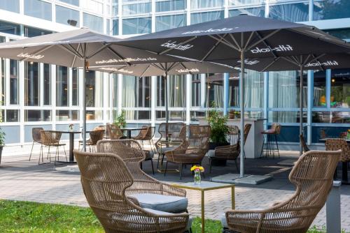 哈尔伯格摩斯Flightgate Munich Airport Hotel, a member of Radisson Individuals的庭院配有桌椅和遮阳伞。