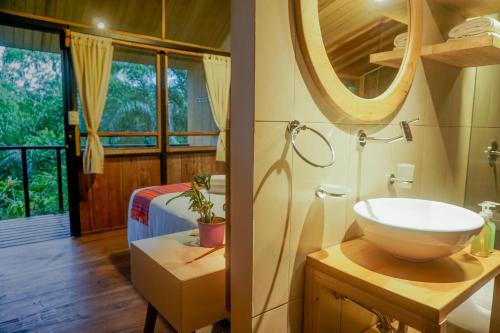 ArchidonaPacha Eco Lodge Glamping & Hotel的一间带水槽和镜子的浴室以及一张床