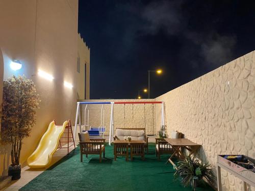 Umm al ‘AmadSHAIKHA villa的天井配有桌椅和滑梯。