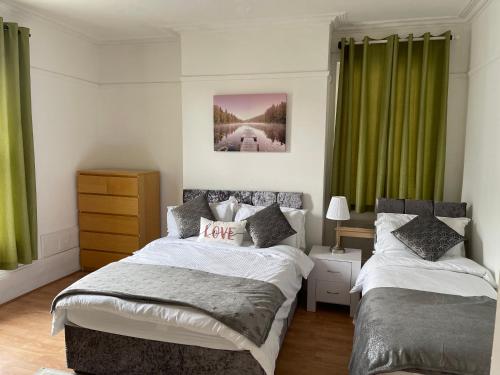 梅德斯通Spacious 4-bed Holiday Home in the heart of Maidstone的一间卧室设有两张床和绿色窗帘