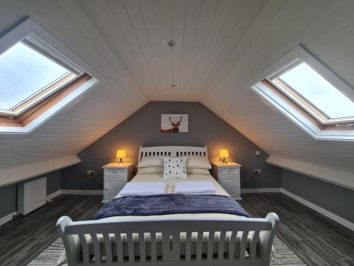 奥马Kingarrow Cottage的阁楼卧室设有1张床和2扇窗户