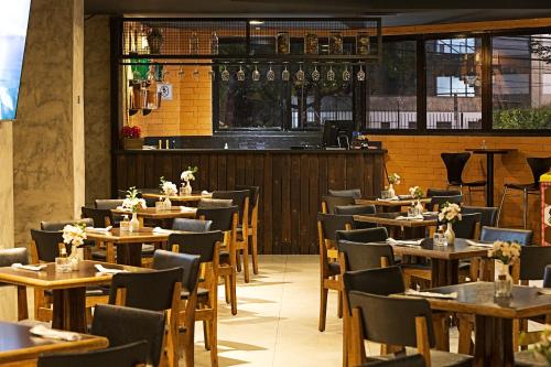 圣保罗泛美经典西金波利斯酒店的一间带木桌椅的餐厅和一间酒吧