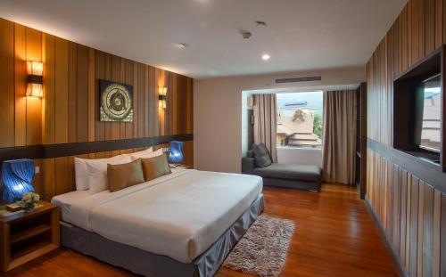 清迈Khum Phucome Hotel -SHA Extra Plus的一间卧室,卧室内配有一张床和一把椅子