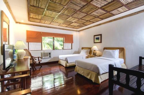 长滩岛海风度假酒店的一间卧室配有两张床、一张桌子和一台电视。