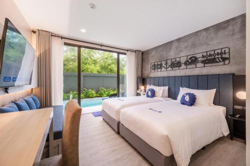 奈扬海滩Kokotel Phuket Nai Yang Beach - SHA Extra Plus的酒店客房设有两张床和一张桌子。