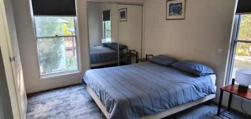彩虹海滩Shelleys House的一间卧室设有一张床和两个窗户。