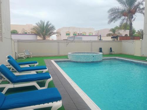 拉斯阿尔卡麦Oasis Hotel Apartment的一座带躺椅的游泳池位于大楼旁