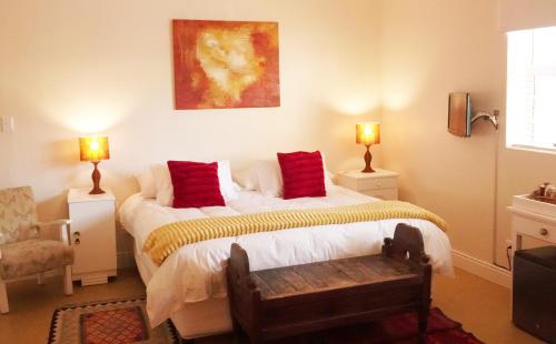 开普敦海豚宾馆的一间卧室配有一张带红色枕头的床