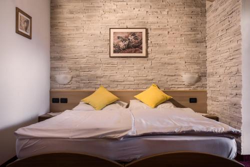 维哥迪法萨索恩索尔酒店的一张带两个黄色枕头和砖墙的床