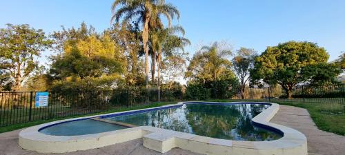 金皮Y Motels Gympie的一个带围栏和树木的庭院内的游泳池