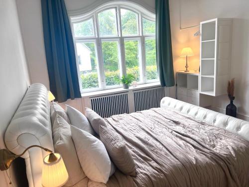 BronshojVilla Apartment near City Centre的卧室配有带枕头的白色床和窗户。