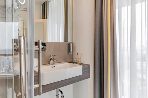 柏林柏林斯皮格尔腾精选酒店的浴室设有白色水槽和镜子