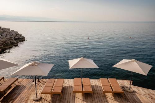 奥帕提亚Hotel Istra - Liburnia的水面上带椅子和遮阳伞的码头