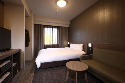 冈山Dormy Inn Okayama Natural Hot Spring的酒店客房,配有床和沙发