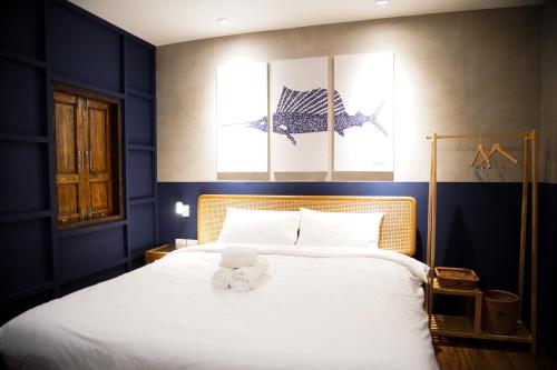 芭堤雅市中心Tali-Yailai Hostel的卧室配有白色大床和蓝色的墙壁