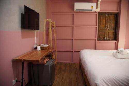 芭堤雅市中心Tali-Yailai Hostel的卧室设有粉红色的墙壁、一张床和一张书桌