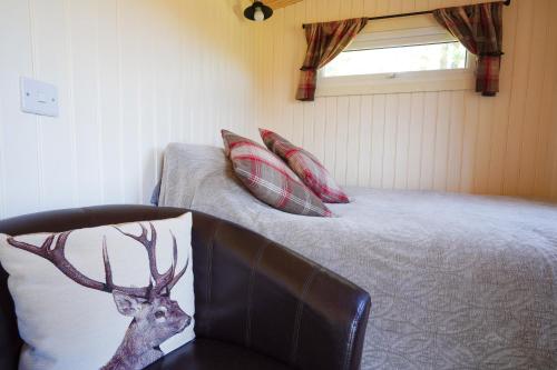 Upper HulmeThe Laburnum Retreat Shepherd Hut private hot Tub的一间卧室配有一张床和一把带鹿枕头的椅子