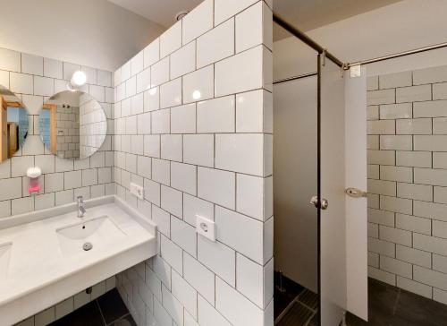 塞维利亚The Nomad Hostel&Pension的白色瓷砖浴室设有水槽和淋浴