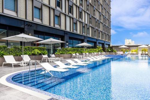 那霸嘉新酒店的酒店游泳池配有白色椅子和遮阳伞