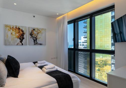 巴特亚姆YalaRent sea-breeze penthouse with jacuzzi的一间卧室设有一张床和一个大窗户
