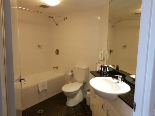 悉尼Parramatta Hotel Apartment的浴室配有卫生间、盥洗盆和浴缸。