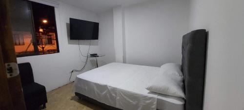 佩雷拉Confortable apartaestudio en excelente ubicación的卧室配有白色的床和平面电视。