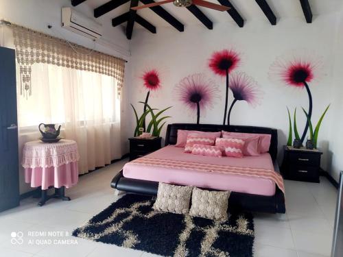 CaucasiaCasa Campo Emaus的卧室配有粉红色的床,墙上挂着鲜花