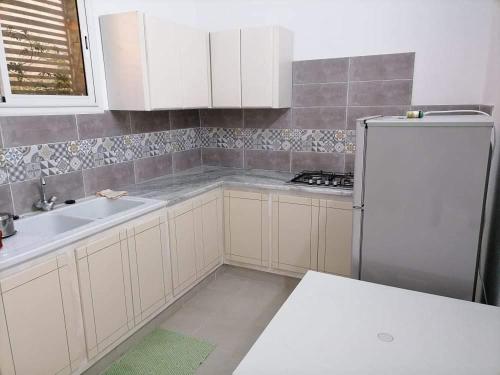 古莱比耶Maison a louer à kelibia的厨房配有白色橱柜和白色冰箱。