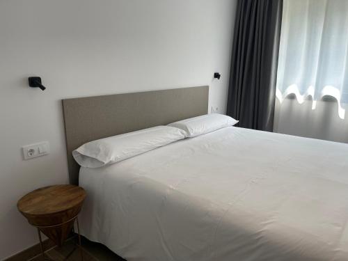 利亚内斯APARTAMENTOS TURÍSTICOS EL RINCONÍN的卧室配有一张白色的大床和一张桌子