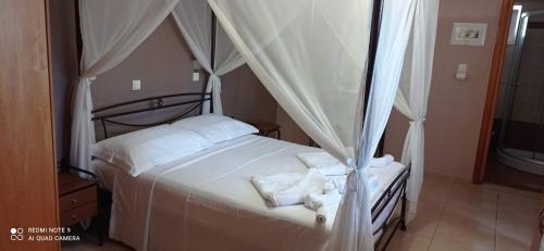 凯法洛斯萨瓦斯公寓式酒店的卧室配有带白色床单的天蓬床